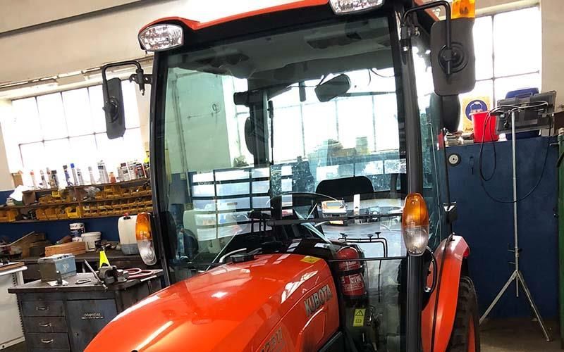 Ein orangefarbener Traktor steht in einer Garage.