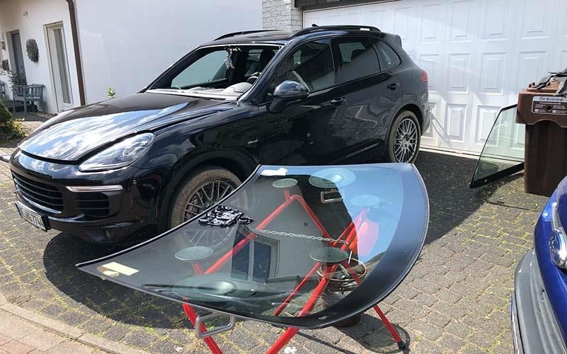 Vor einer Garage steht ein schwarzes Auto mit einer Windschutzscheibe auf einem Ständer.