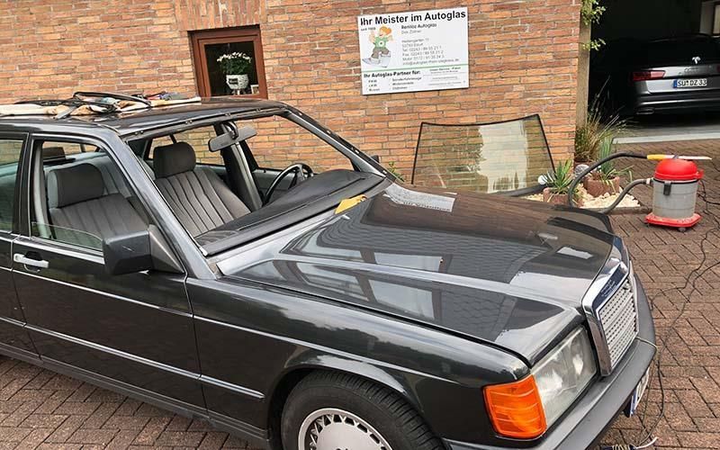Ein schwarzes Auto parkt vor einem Backsteingebäude.