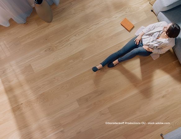 Frau sitzt auf einem Laminatboden