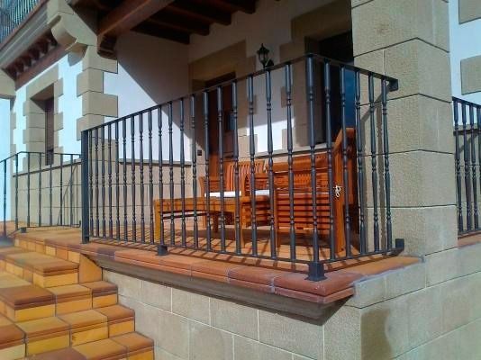 Un balcón con barandilla de hierro forjado y escaleras.