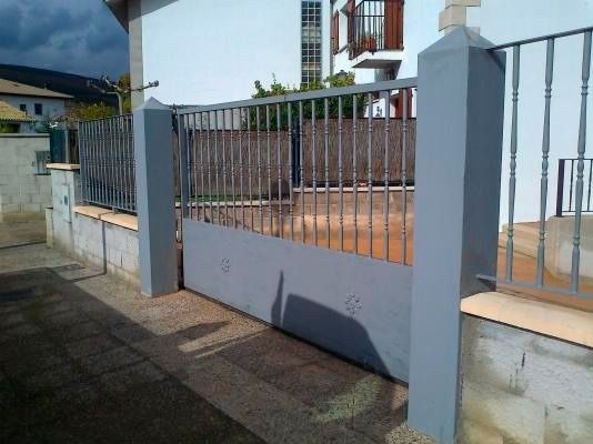 Una valla con una puerta corrediza delante de una casa