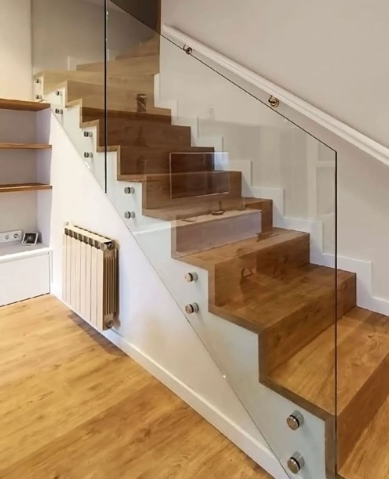 Una escalera de madera con barandilla de vidrio transparente.