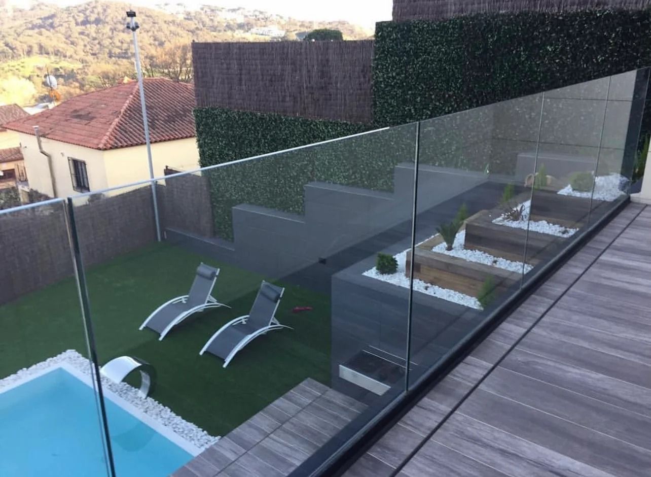 Un balcón con barandilla de cristal con vistas a una piscina.