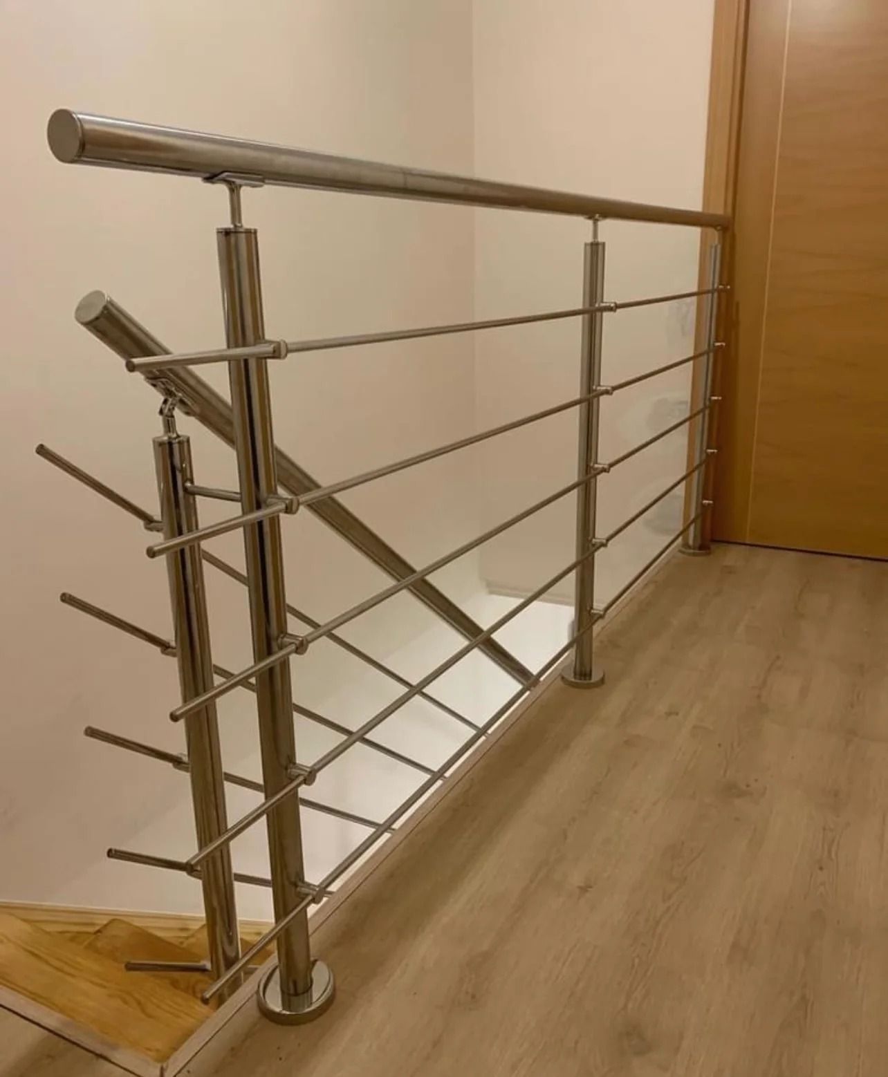 Una escalera con barandilla de acero inoxidable y escalones de madera