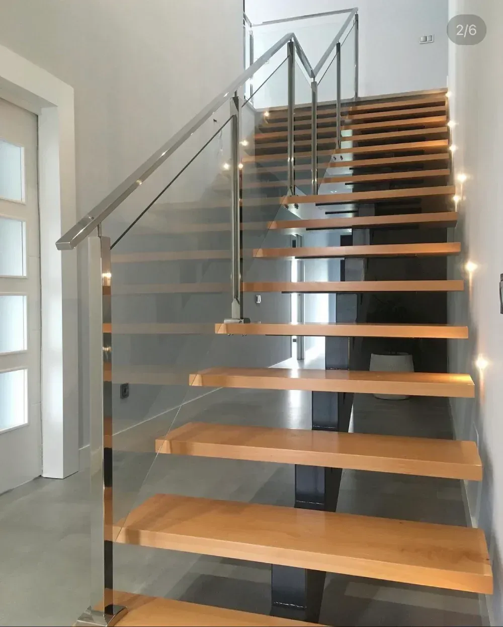 Una escalera de madera con barandilla de vidrio transparente.