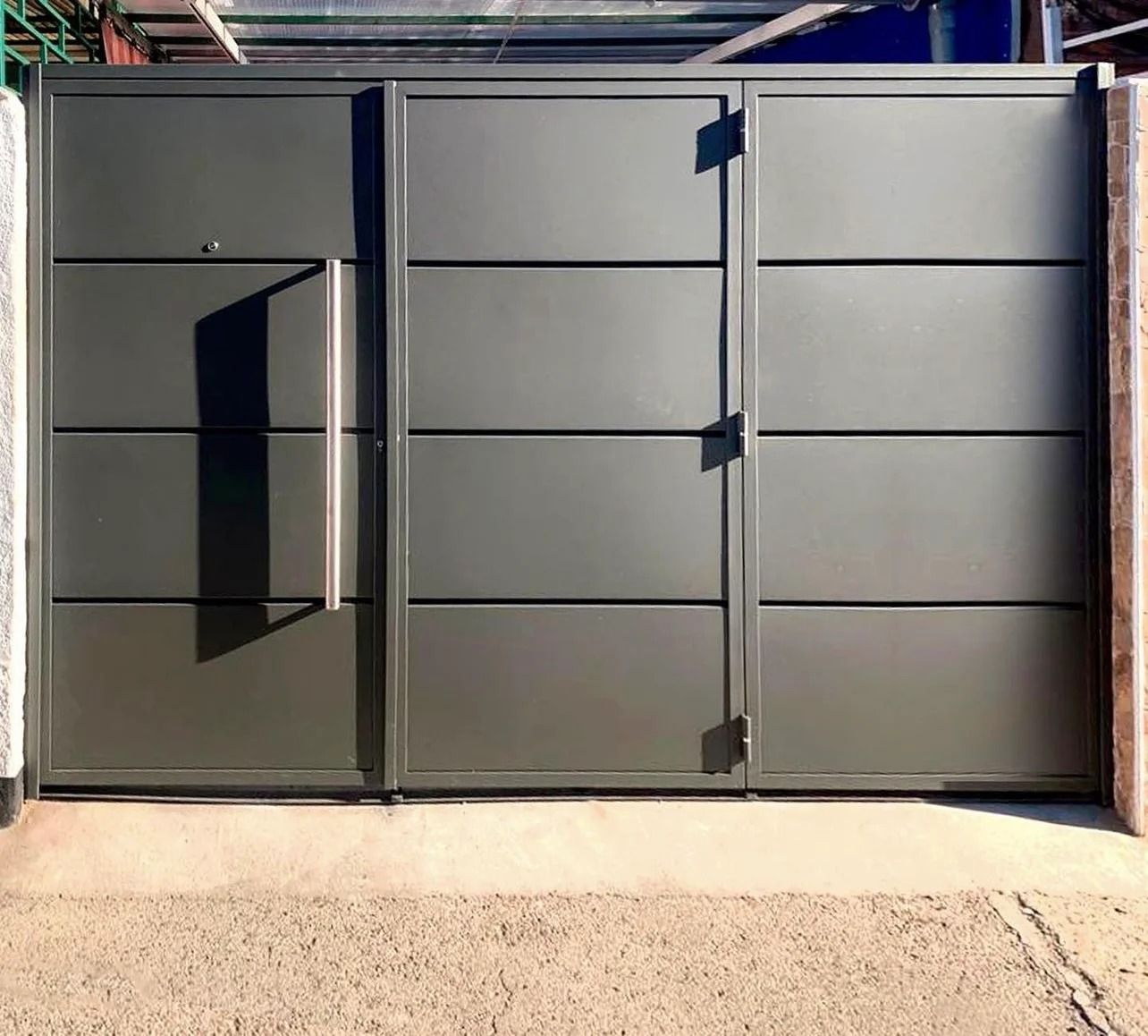 Una gran puerta de metal gris se encuentra encima de un camino de grava.