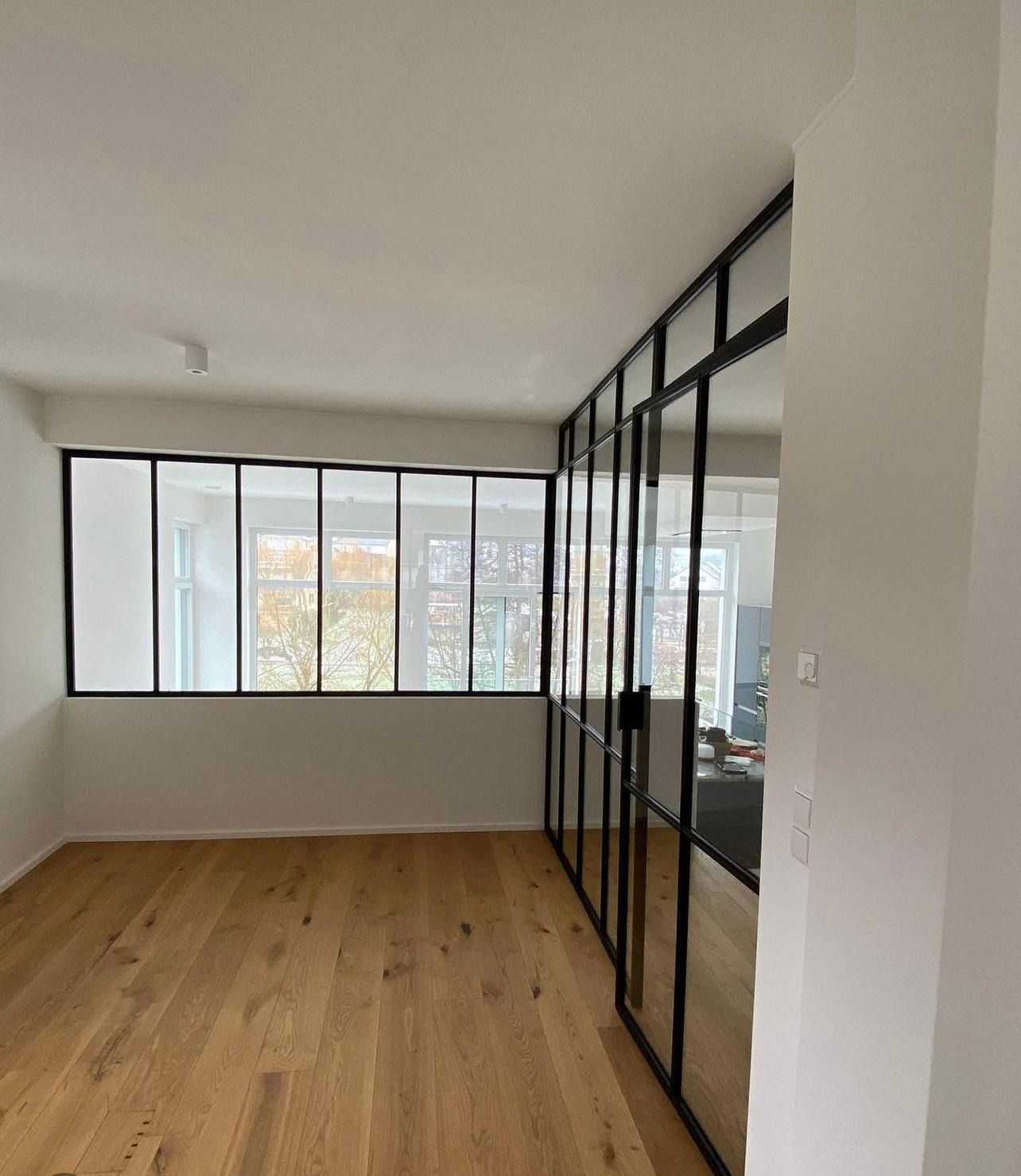 Una sala de estar con pisos de madera y muchas ventanas.