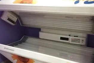 Una cama de bronceado vacía con un girasol encima en una habitación.