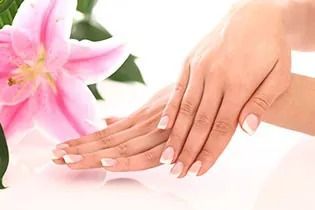 Un primer plano de las manos de una mujer con una flor rosa en el fondo.