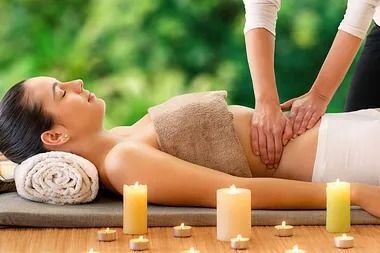 Una mujer está recibiendo un masaje en un spa rodeada de velas.