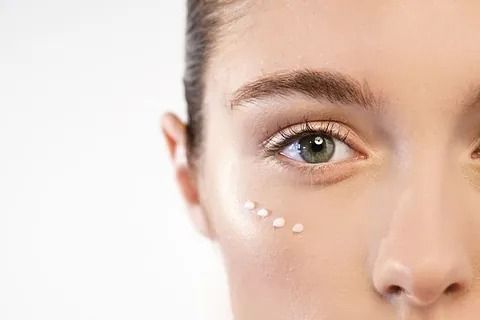 Un primer plano de una mujer aplicándose crema para los ojos.