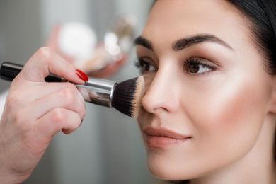 Una mujer se está maquillando con un maquillador.