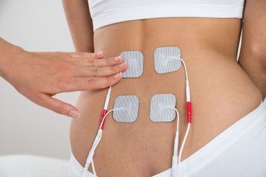 Una mujer está recibiendo un tratamiento de electroterapia en la espalda.