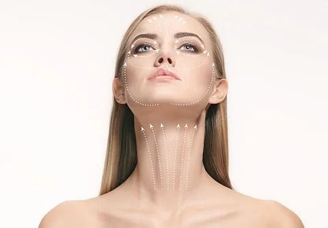 Una mujer con líneas dibujadas en la cara y el cuello mira hacia arriba.