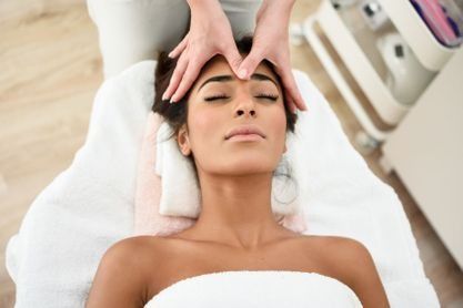 Una mujer está recibiendo un masaje de cabeza en un spa.
