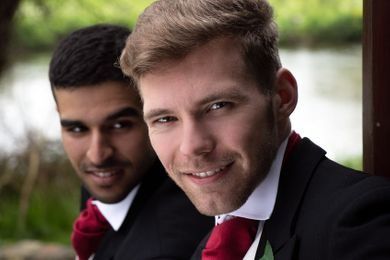 Dos hombres con traje y corbata roja posan para una fotografía.