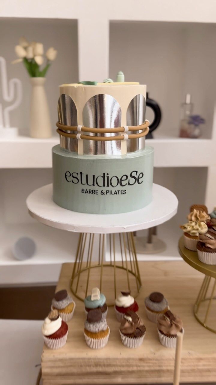 Un pastel colocado encima de una mesa al lado de cupcakes.