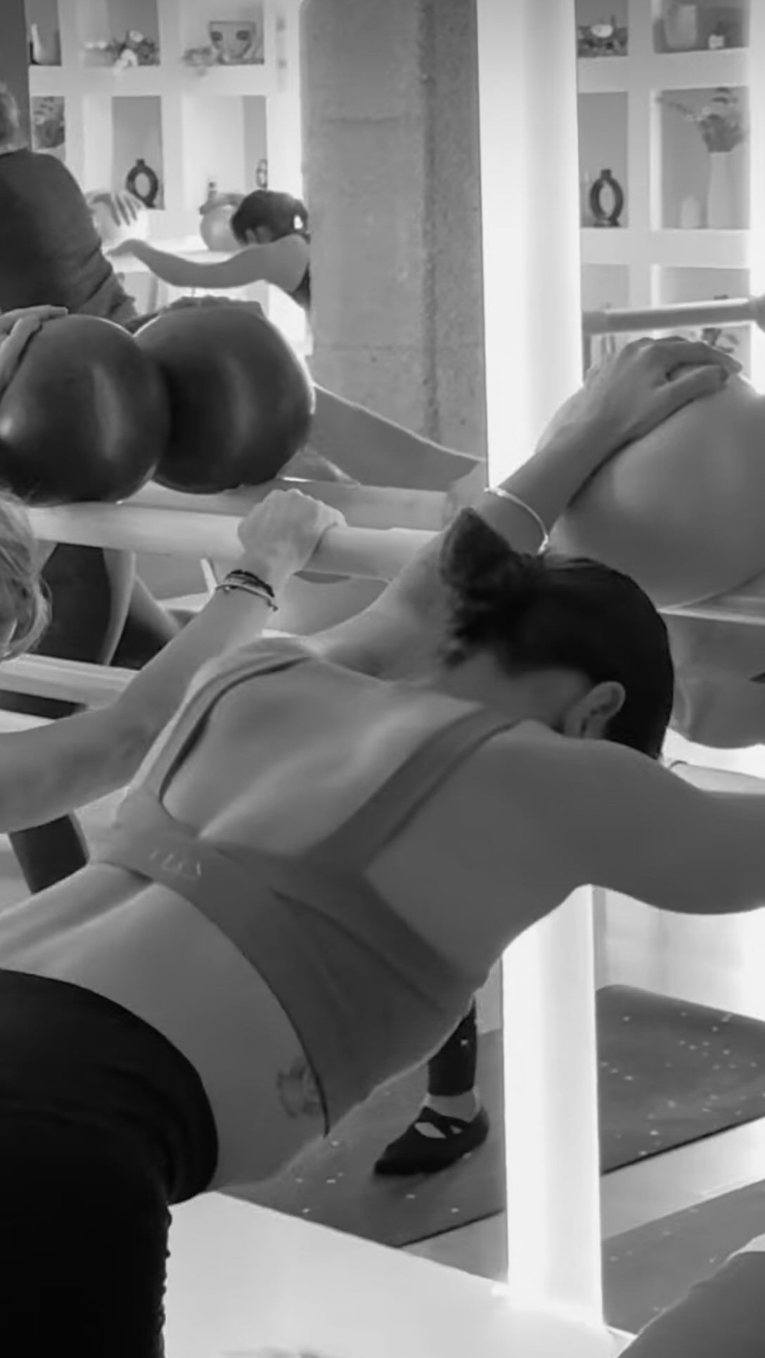 Una fotografía en blanco y negro de una mujer haciendo ejercicios en un gimnasio.