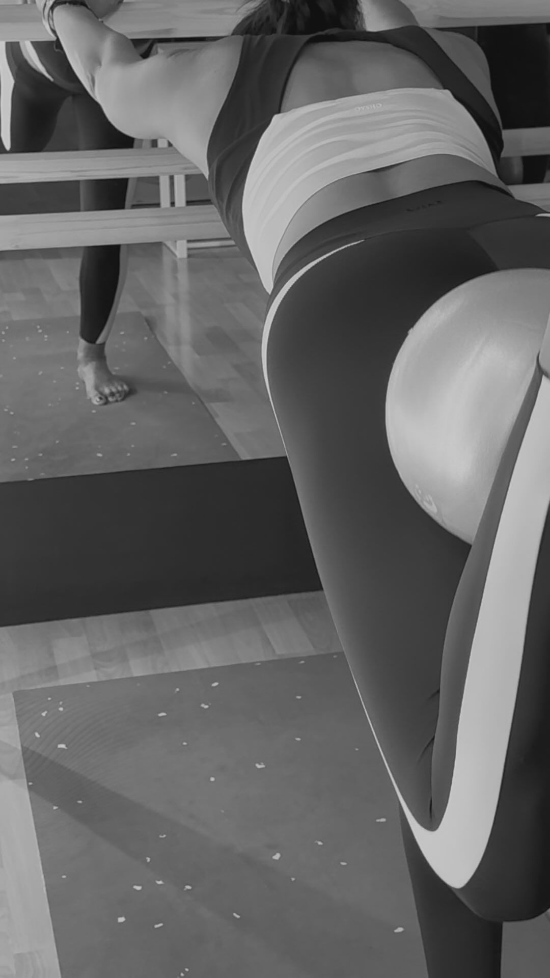 Una mujer estira las piernas sobre una esterilla de yoga frente a un espejo.