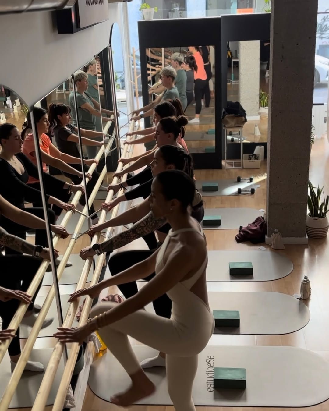 Un grupo de personas está practicando yoga frente a un espejo.