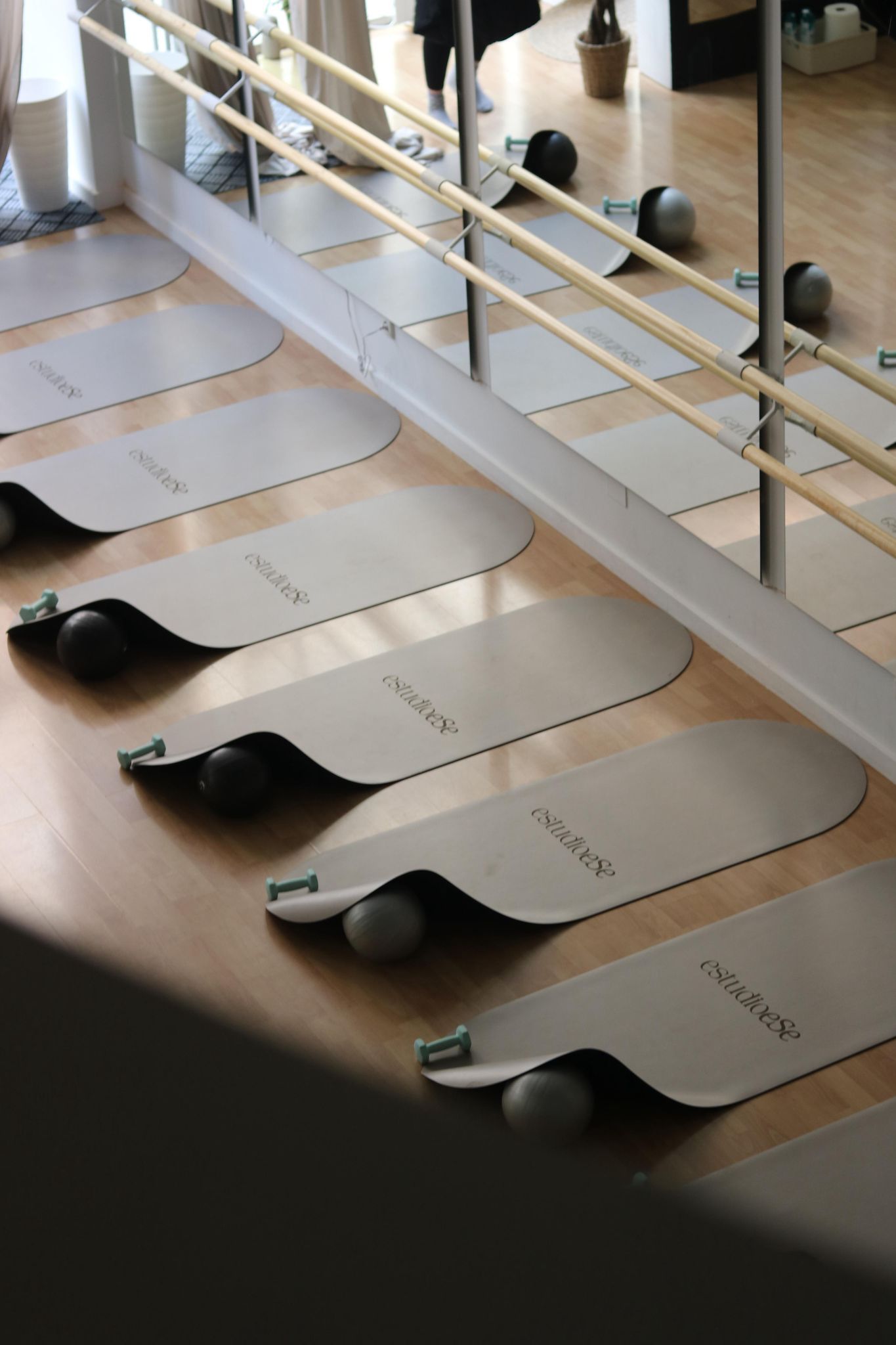 Una fila de colchonetas de yoga están alineadas frente a un espejo en un gimnasio.