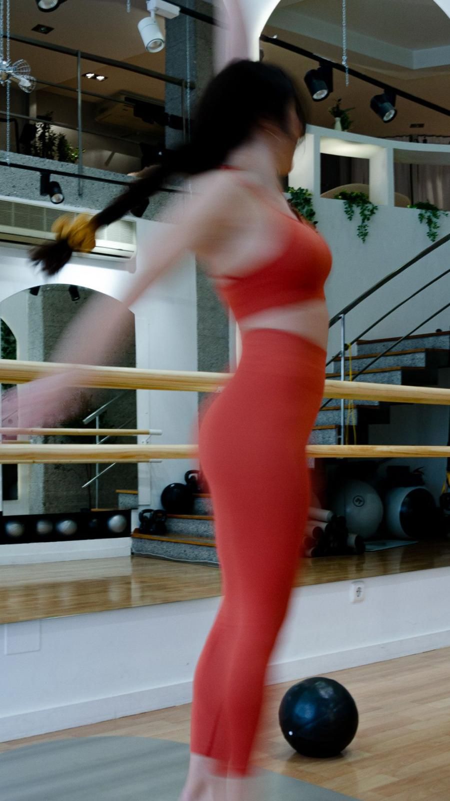 Una mujer con leggings rojos está parada frente a un espejo.