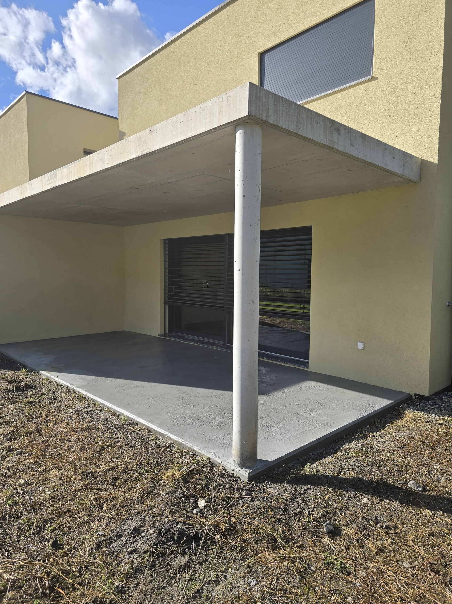 Vue de la façade d'une maison avec des fenêtres, portes-fenêtres et une terrasse couverte