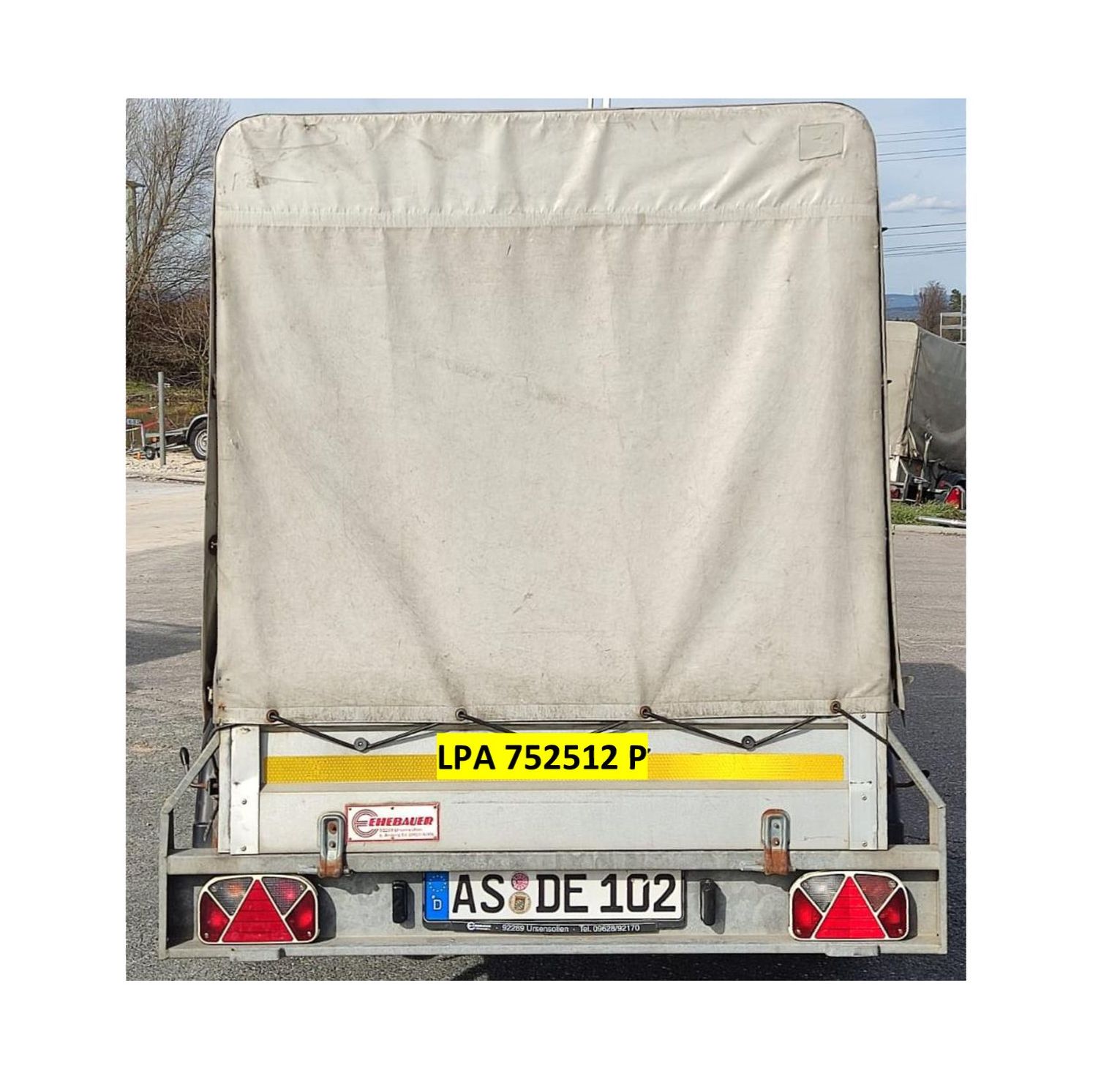 Rückansicht eines weißen LKW mit Plane, mit den Kennzeichen „AS DE 102“ und „LPA 752512 P“.