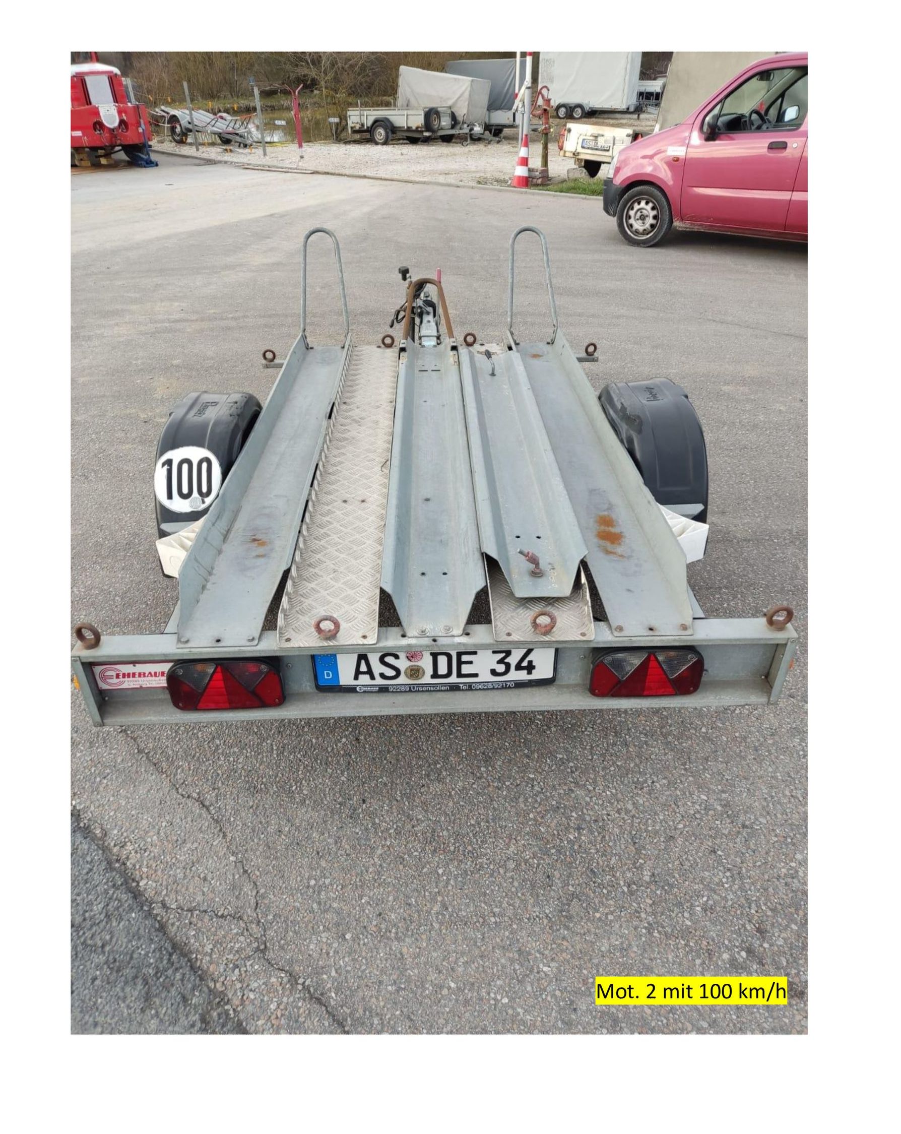 Rückansicht eines kleinen Anhängers mit zwei Rampen zum Transport von Motorrädern. Kennzeichen: AS DE 34.