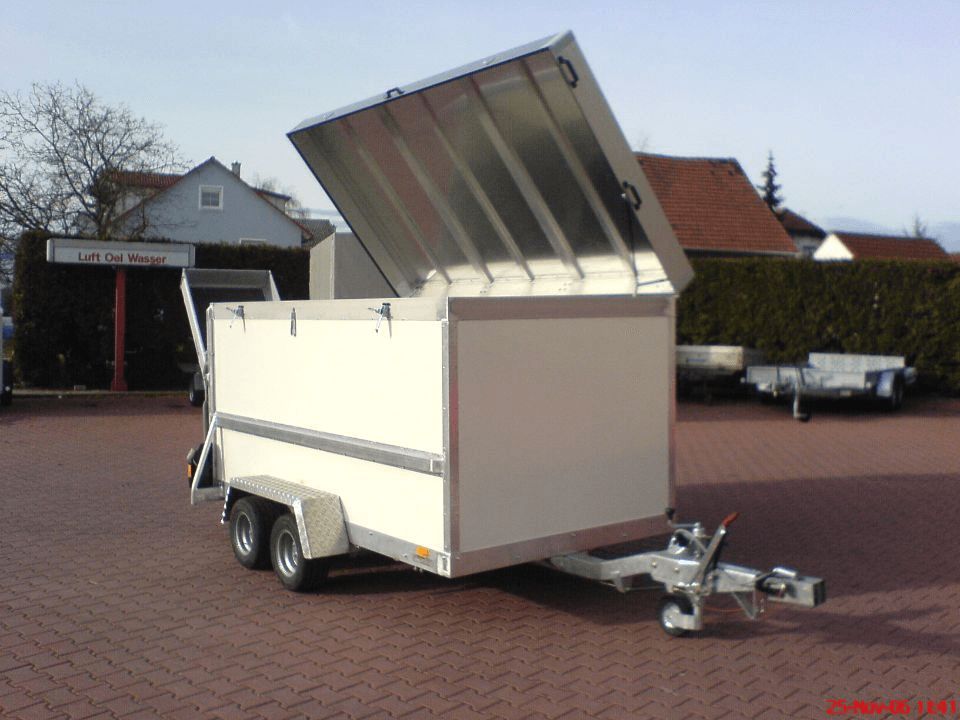 Weißer Kastenanhänger mit erhöhtem Metalldeckel auf einer Ziegeloberfläche.