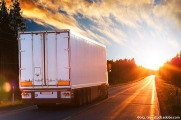 Ein Sattelschlepper fährt eine Straße entlang in Richtung Sonnenuntergang.