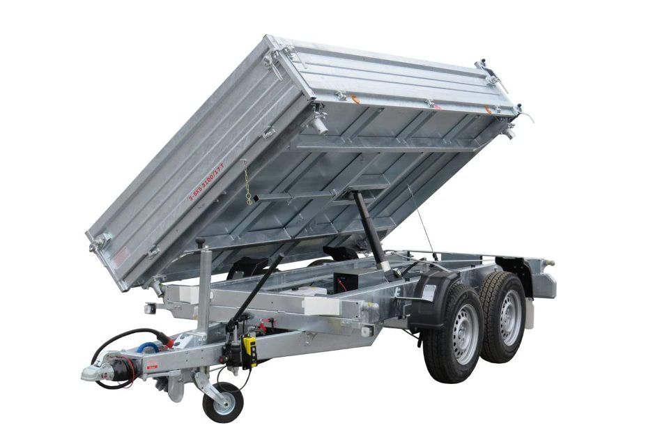 Grauer Kippanhänger, nach oben gekippt, sodass sein Inhalt zu sehen ist.