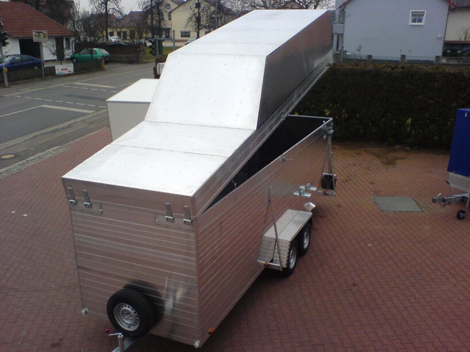 Aluminiumanhänger mit erhöhtem Dachpaneel auf einer Ziegeloberfläche.