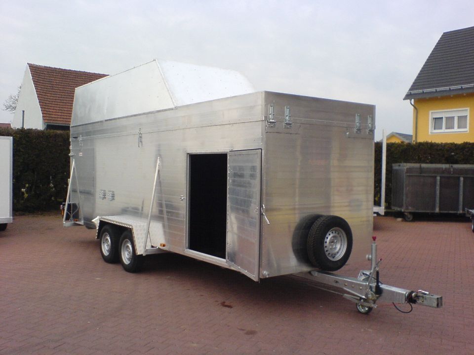 Aluminium-Pferdeanhänger mit weißem Dach, im Freien geparkt.