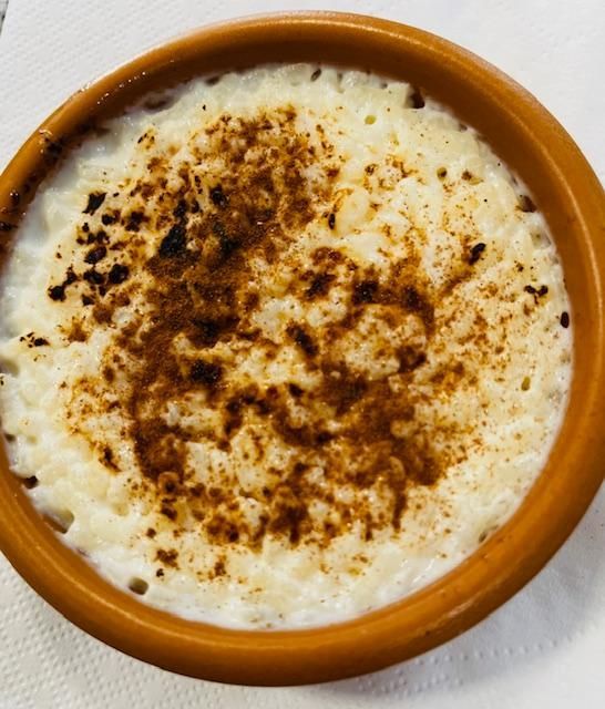 Arroz con leche en cuenco de barro marrón, con cobertura caramelizada.