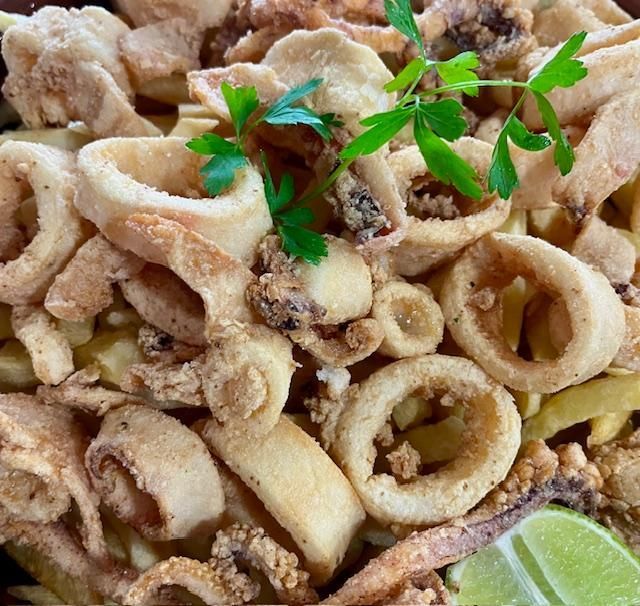 Calamares fritos y patatas fritas con perejil y lima.