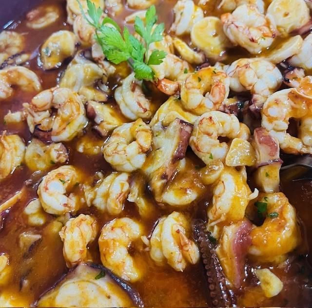 Guiso de mariscos con guarnición de camarones, pulpo y perejil en salsa marrón.