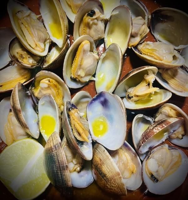 Almejas cocidas en concha con rodaja de limón.