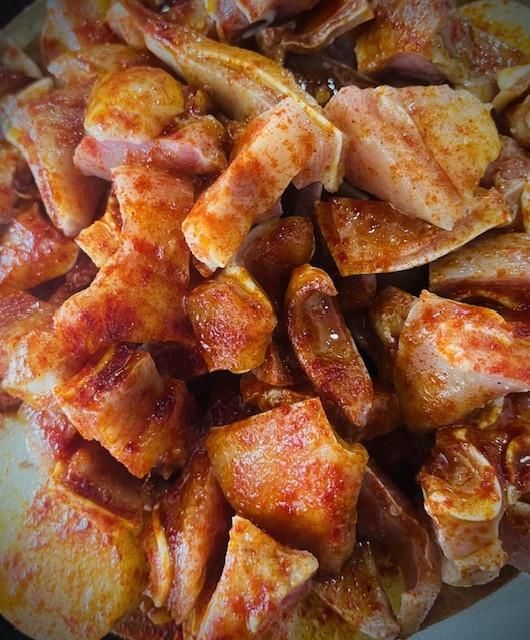 Primer plano de trozos de carne cortados y sazonados con una especia de color marrón rojizo.