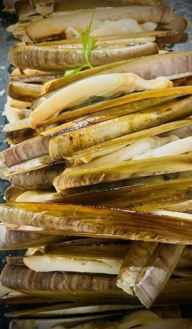 Montón de navajas a la plancha, con conchas de color marrón claro y oscuro.