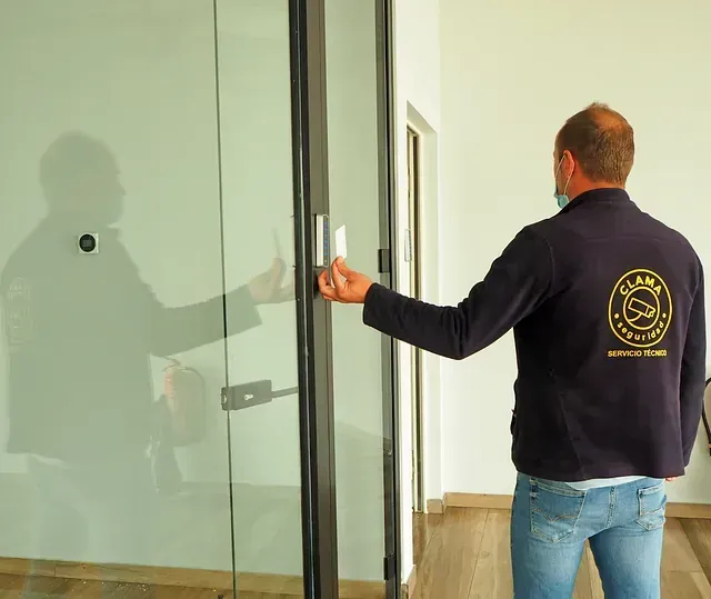 Un hombre que lleva una chaqueta negra con un logo en la espalda abre una puerta de cristal.