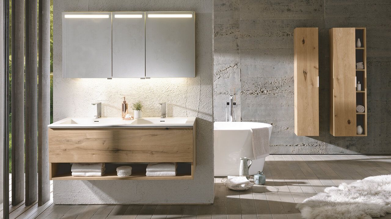 Moderner Badezimmerschrank mit Holzmöbeln, zwei Waschbecken, verspiegelten Wandschränken und einer angrenzenden Badewanne.