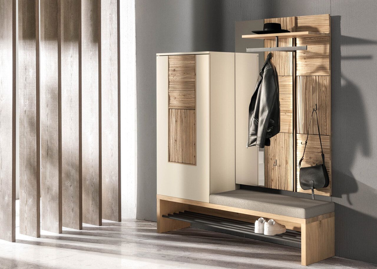 Eine moderne Garderobe für den Flur mit einer hellen Holzbank, einem grauen gepolsterten Sitz, einem Aufbewahrungsschrank und Haken für Kleidung.