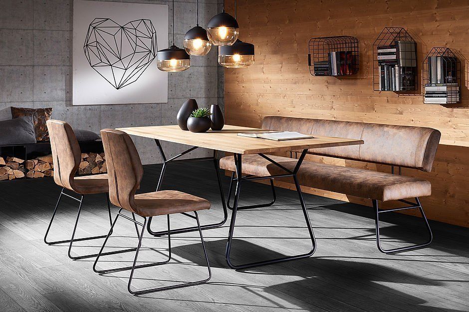 Essbereich mit einem Holztisch mit schwarzen Metallbeinen, einer passenden langen Bank, zwei Stühlen und Pendelleuchten.