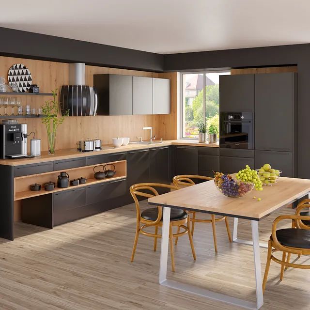 Moderne Küche mit dunklen Schränken, holzfarbenen Arbeitsplatten und Regalen sowie einem Esstisch mit Stühlen in einem sonnigen Raum.