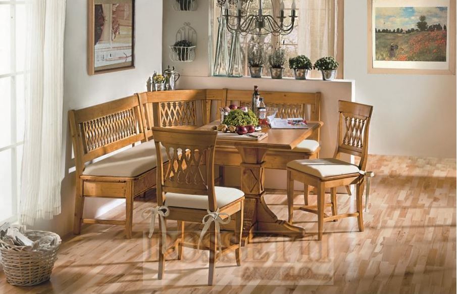 Eine gemütliche Essecke aus Holz mit Eckbank, Tisch und zwei Stühlen mit cremefarbenen Kissen auf Holzboden.