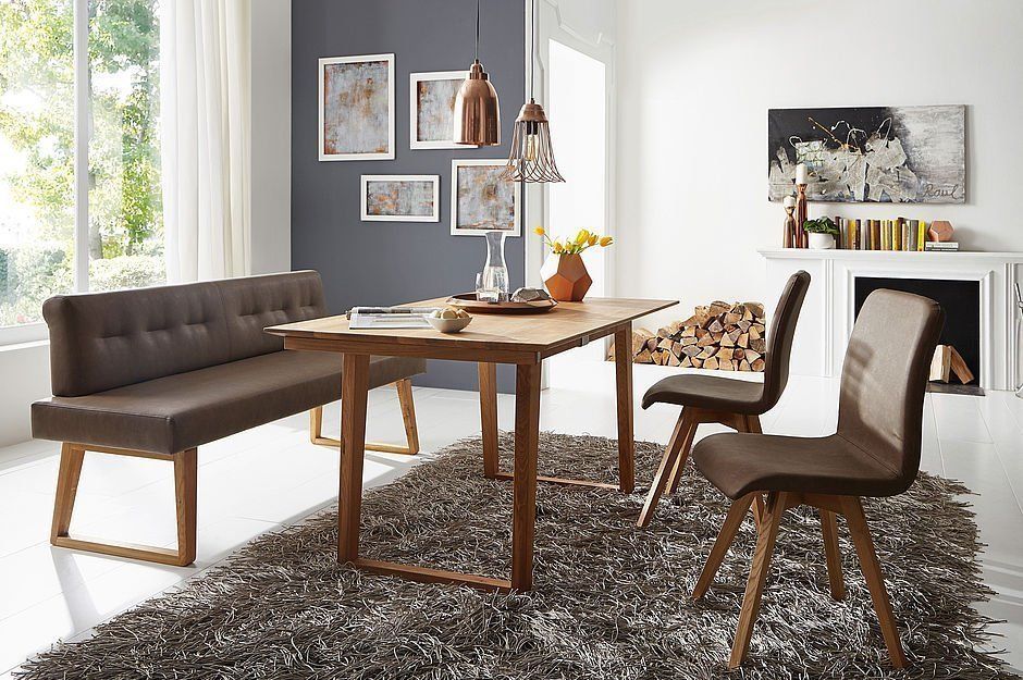 Ein moderner Essbereich mit Holztisch, braun gepolsterter Bank, zwei passenden Stühlen und einem strukturierten Teppich.