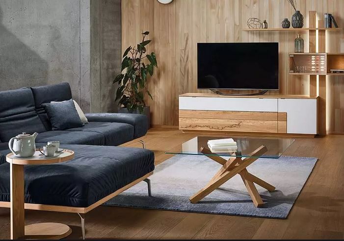 Ein modernes Wohnzimmer mit einer marineblauen Eckcouch, einem Couchtisch aus Glas und einer holzgetäfelten Wand mit einem Flachbildfernseher-Ständer.