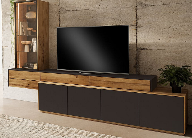 Unterhalb eines Fernsehers, neben einem hohen, holzgerahmten Display, befindet sich eine an der Wand montierte Medienkonsole mit Holzschubladen und dunkelgrauen Türen.